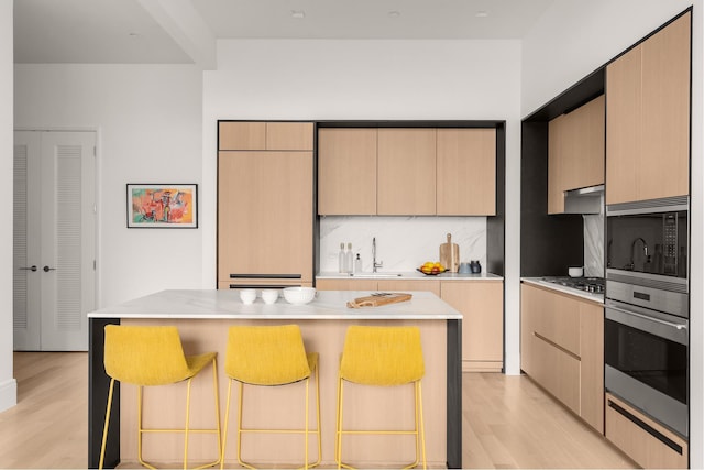 kitchen featuring appliances with stainless steel finishes, a breakfast bar area, a kitchen island, and light wood-style floors