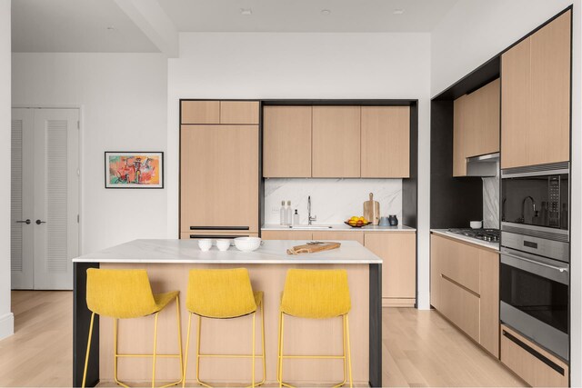 kitchen featuring appliances with stainless steel finishes, a sink, a breakfast bar, and light wood finished floors