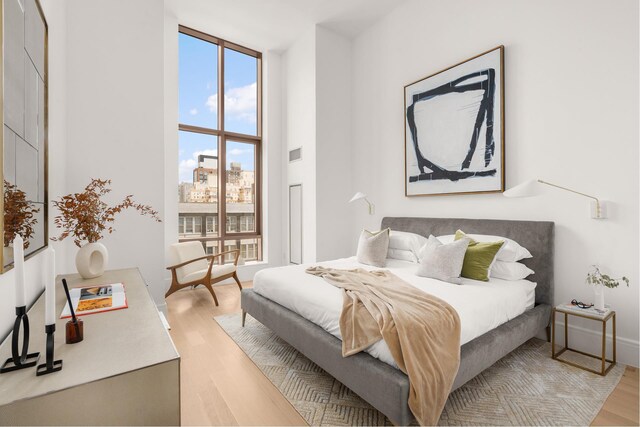 bedroom with light wood-type flooring and a towering ceiling