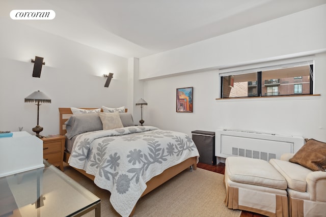 bedroom with visible vents, radiator heating unit, and wood finished floors