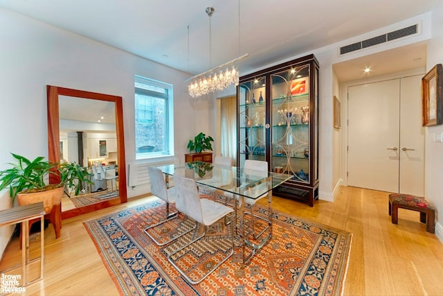 dining room with light hardwood / wood-style floors and a chandelier