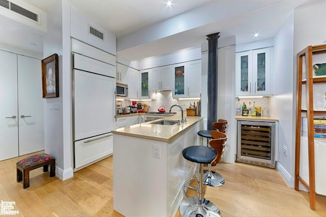 kitchen with white cabinetry, paneled fridge, wine cooler, and kitchen peninsula