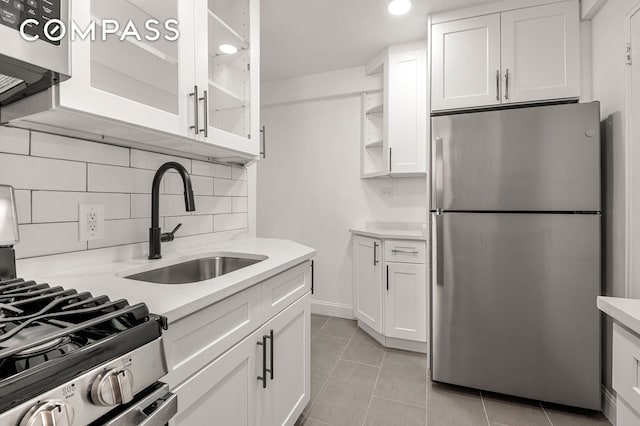 kitchen with appliances with stainless steel finishes, white cabinets, light countertops, and glass insert cabinets