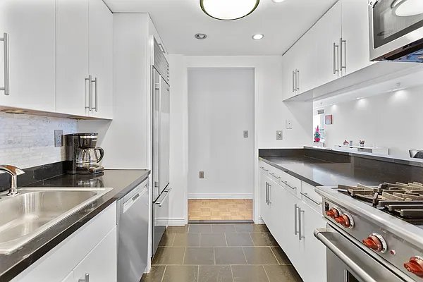 kitchen with recessed lighting, premium appliances, dark countertops, and a sink