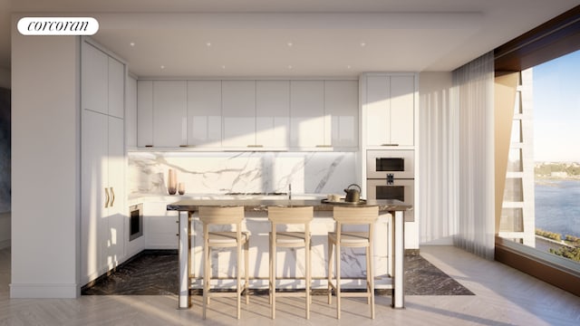 kitchen with white cabinets, a center island, a kitchen breakfast bar, stainless steel oven, and dark parquet floors