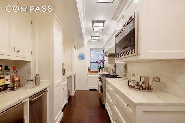 kitchen with appliances with stainless steel finishes, white cabinetry, backsplash, ornamental molding, and light stone countertops