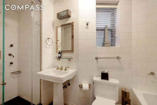 full bathroom featuring a shower with door, a tub, toilet, tile walls, and a sink