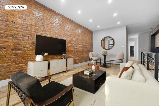 living room featuring a baseboard heating unit, light hardwood / wood-style floors, and brick wall