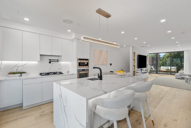 kitchen featuring a spacious island, white cabinetry, hanging light fixtures, gas cooktop, and expansive windows