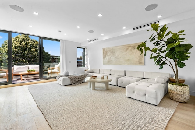 living room featuring a wall of windows, recessed lighting, visible vents, and light wood-style flooring