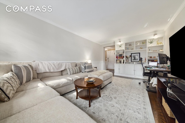 living room with wainscoting, wood finished floors, built in features, and crown molding