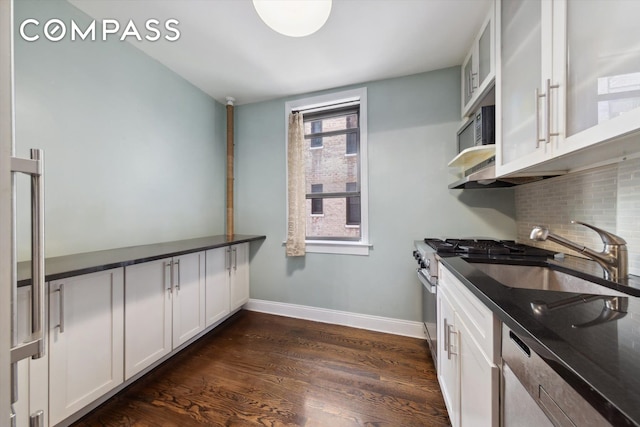 kitchen with baseboards, dark wood finished floors, stainless steel microwave, white cabinetry, and backsplash