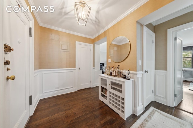 entryway featuring a notable chandelier, wainscoting, dark wood-type flooring, and ornamental molding