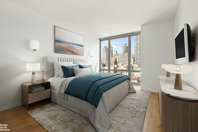 bedroom featuring floor to ceiling windows and light wood-type flooring