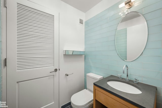 bathroom with tasteful backsplash, vanity, and toilet