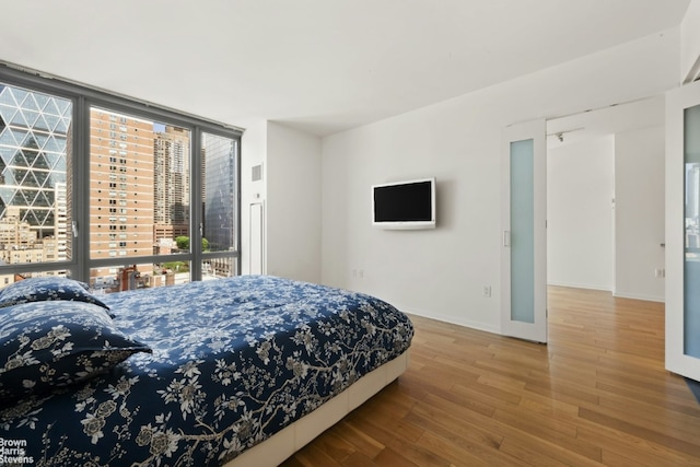 bedroom with hardwood / wood-style flooring and floor to ceiling windows