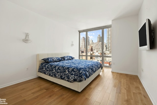 bedroom featuring expansive windows and hardwood / wood-style flooring