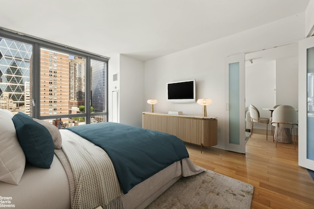 bedroom featuring radiator heating unit, light hardwood / wood-style flooring, and floor to ceiling windows