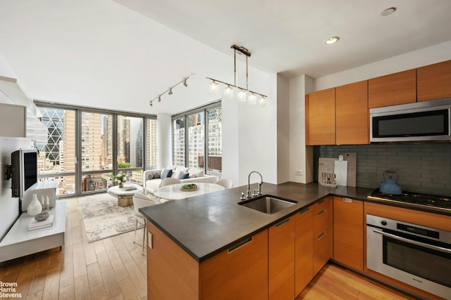 kitchen featuring sink, decorative light fixtures, appliances with stainless steel finishes, kitchen peninsula, and decorative backsplash