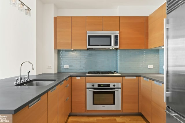 kitchen featuring sink, tasteful backsplash, light hardwood / wood-style flooring, kitchen peninsula, and stainless steel appliances