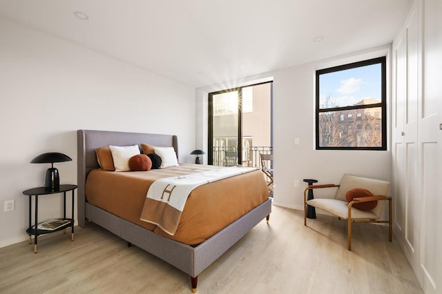 bedroom with access to outside, light wood-style flooring, and baseboards