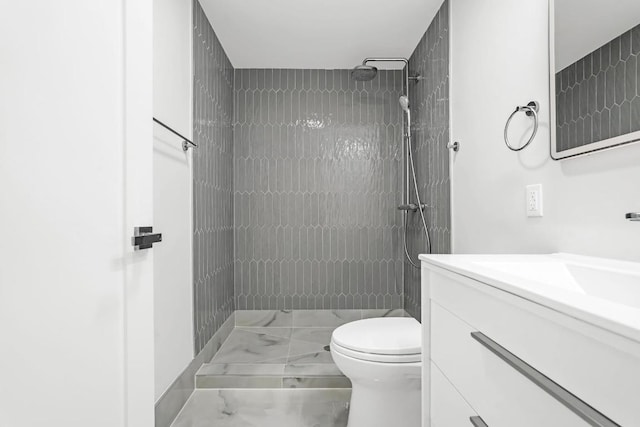 bathroom featuring toilet, marble finish floor, a stall shower, and vanity