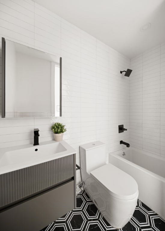 full bathroom featuring tiled shower / bath, tile walls, vanity, and toilet