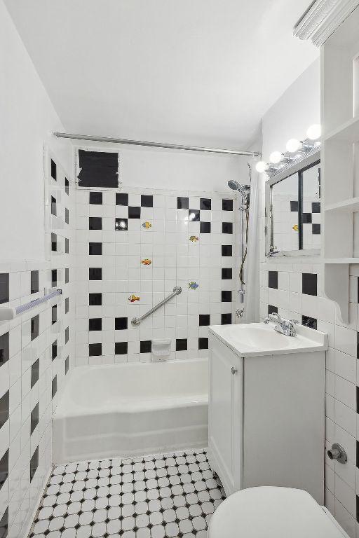 full bathroom featuring toilet, tile walls, shower / bathtub combination with curtain, and vanity