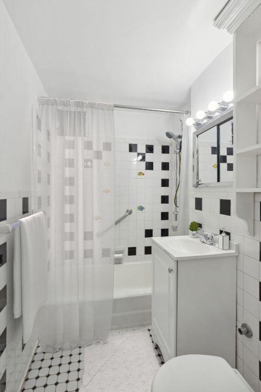 full bathroom with tile patterned floors, toilet, tile walls, shower / tub combo with curtain, and vanity