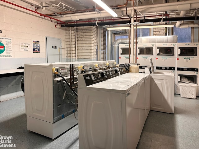 common laundry area with washer and dryer and concrete block wall