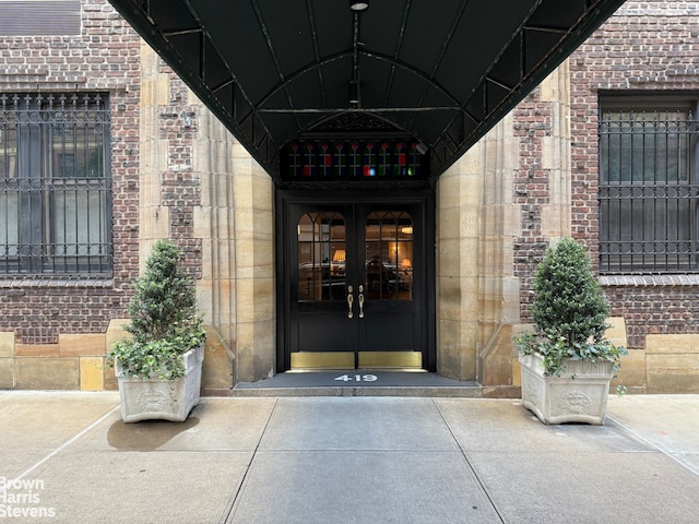 view of exterior entry featuring french doors and brick siding