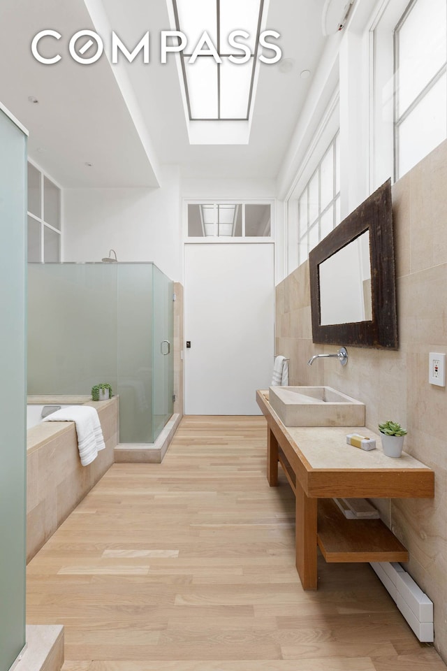 bathroom featuring a bath, wood finished floors, a stall shower, and a sink