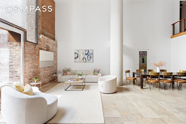 living area featuring brick wall and a high ceiling