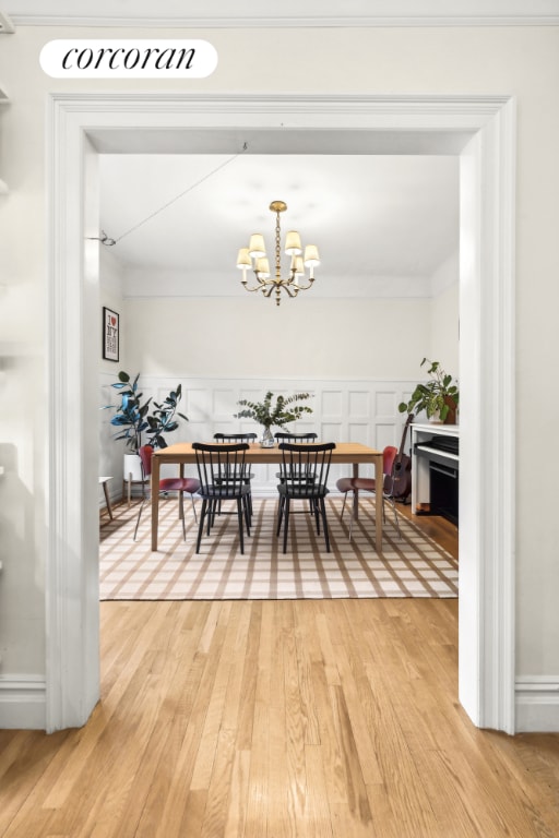 dining area featuring a notable chandelier, ornamental molding, and hardwood / wood-style flooring