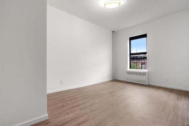 spare room featuring radiator and light hardwood / wood-style flooring