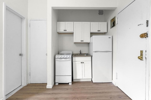 kitchen with sink, white cabinets, white appliances, and light hardwood / wood-style floors