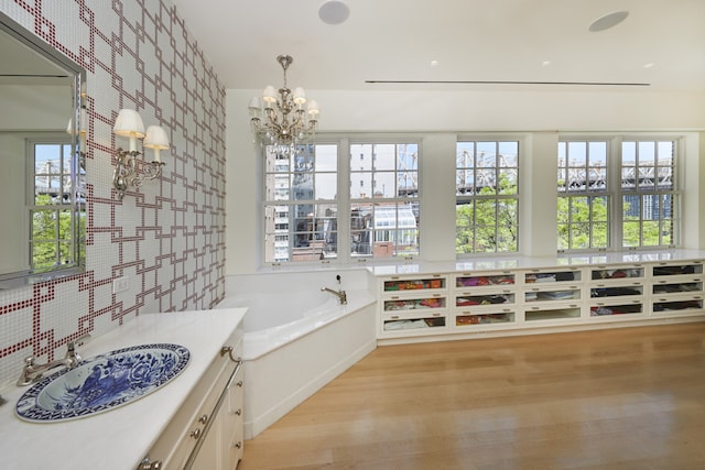 6 Sutton Sq, New York City, NY 10022 - bathroom with wallpapered walls, vanity, wood finished floors, a bath, and a chandelier