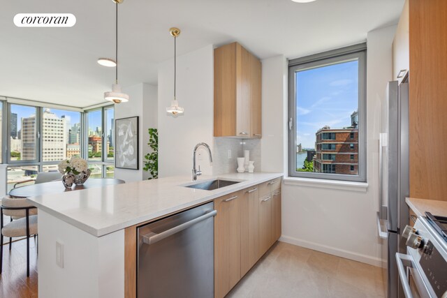 kitchen with visible vents, a peninsula, a view of city, stainless steel appliances, and a sink