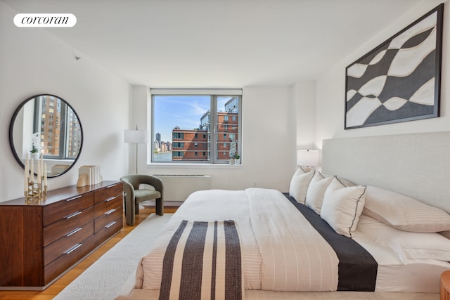 bedroom featuring visible vents, radiator heating unit, and wood finished floors