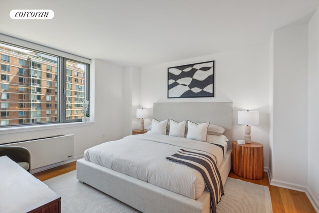 425 Main St Unit 12D, New York City, NY 10044 - bedroom featuring radiator heating unit, baseboards, light wood-style flooring, and visible vents