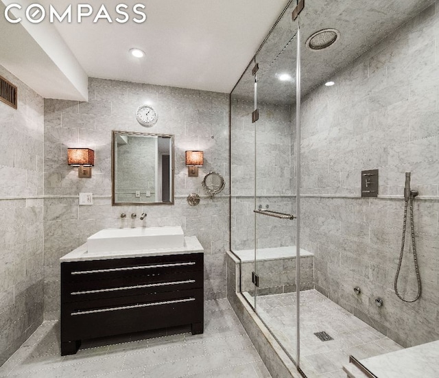 bathroom with vanity, a shower with shower door, and tile walls