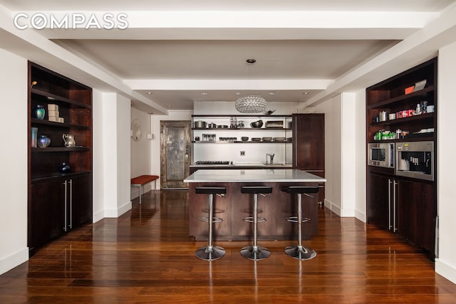 bar with stainless steel microwave, built in shelves, baseboards, and dark wood-style flooring