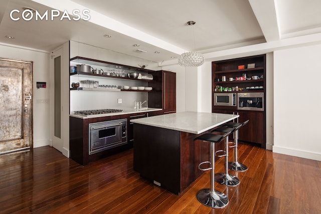 bar with indoor wet bar, stainless steel microwave, gas stovetop, and dark wood-type flooring