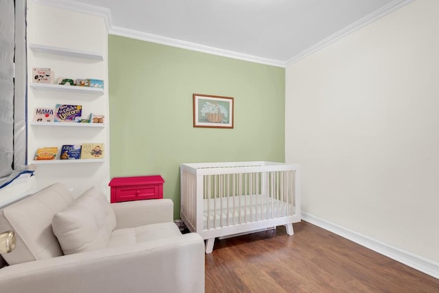 bedroom with a nursery area, crown molding, and dark hardwood / wood-style flooring