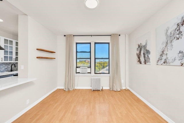 spare room with hardwood / wood-style flooring, sink, and radiator heating unit