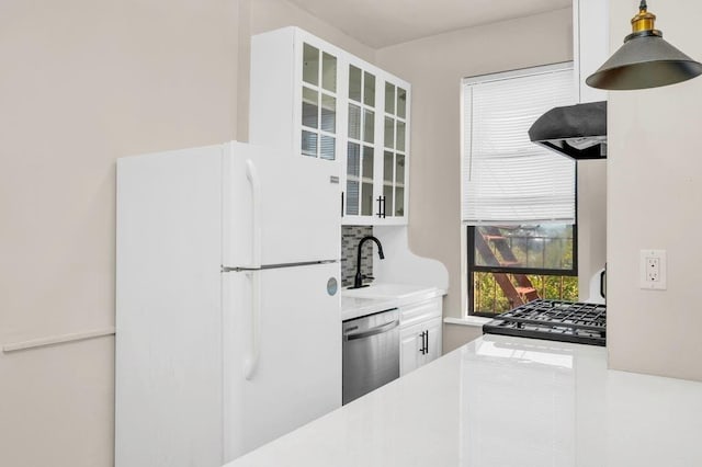 kitchen with exhaust hood, white cabinetry, white fridge, sink, and stainless steel dishwasher