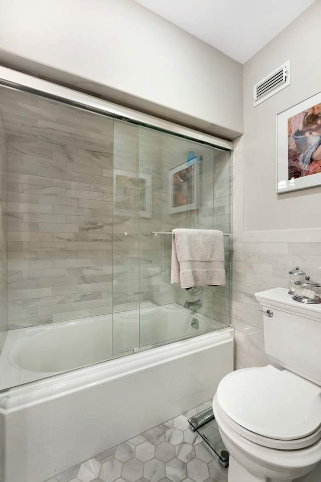 57 E 75th St Unit 2R, New York City, NY 10021 - bathroom featuring shower / bath combination with glass door, toilet, tile patterned flooring, and tile walls