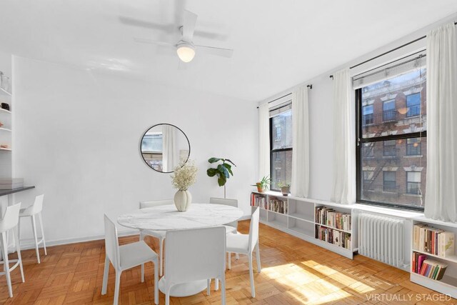 dining space with radiator heating unit, light parquet floors, and ceiling fan