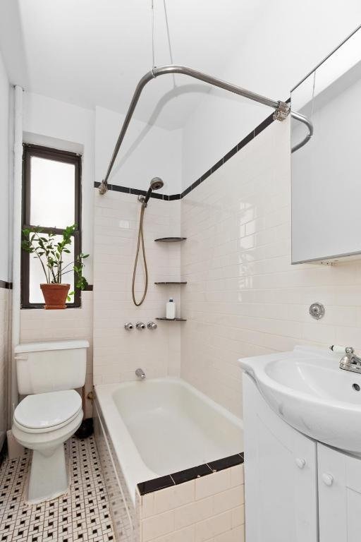 full bathroom with tiled shower / bath combo, vanity, tile walls, and toilet