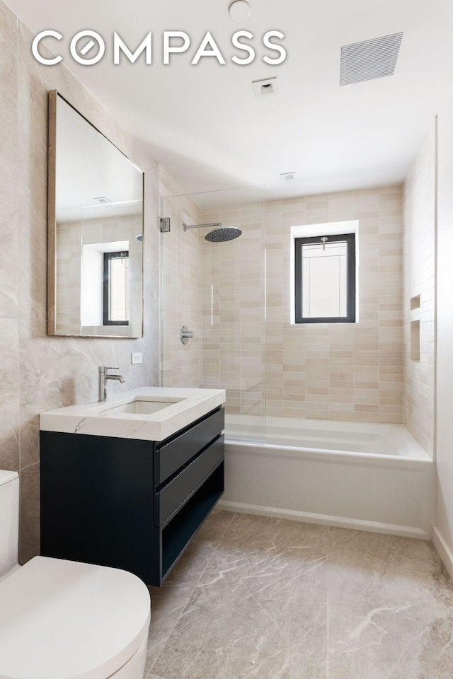 bathroom with toilet, washtub / shower combination, visible vents, and a wealth of natural light